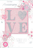 This image captures a romantic anniversary card designed with the same attention to detail you'd expect from Flowers Radlett when creating a bespoke bouquet. At its heart, the word LOVE stands out in softly raised letters, their surface kissed with delicate glitter that sparkles gently rather than dazzling, evoking the faint glow of fairy lights along Radlett's quiet streets. The letters rest on a blush pink panel, subtly deeper than the rest of the card, which adds a sense of depth and importance, almost like a floral focal point framed by foliage. Around this central word, an intricate pattern of stylised blossoms, tiny buds, and curling leaves unfurls in light lines of grey, white, and silver. The flowers themselves are loose and graceful, suggesting roses or springtime blooms without tying themselves to one exact variety, the way a florist might sketch an arrangement concept before selecting the freshest stems. Hints of silver foil catch the light on certain petals and leaves, adding a refined shimmer reminiscent of morning dew in a garden near Shenley. The background is a uniform, gentle pink that softens the whole composition and enhances its dreamy, romantic tone. Delicate scripted text-phrases like On Our Anniversary and a simple declaration of lasting love-winds across the design in an elegant, slightly looping style, echoing the curves of the vines and floral trails. The card feels tender and timeless, like a quiet promise shared at home after flowers have been delivered, capturing the essence of enduring romance within a soft palette of blush, ivory, and silver.